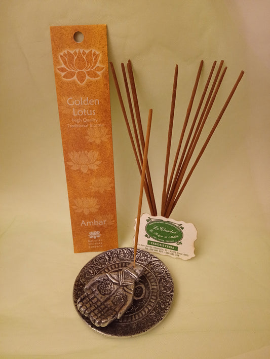 Incenso Amber Ambra Fiore d'Oriente Linea Golden Lotus, astuccio con mazzetto di bastoncini aperti in piedi, portaincenso in metallo con mano e biglietto da visita esposti da Erboristeria La Clessidra Carpi.