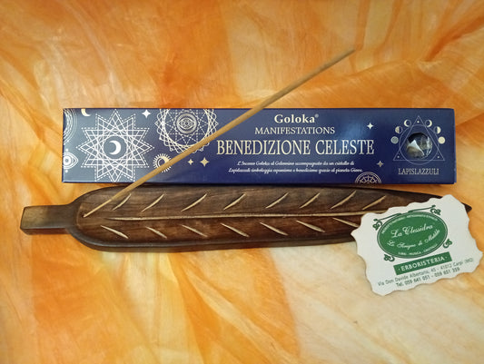 Confezione orizzontale di Incenso Goloka Manifestation Benedizione Celeste con Lapislazzuli burattato, davanti a un portaincenso artigianale a forma di foglia con stick, biglietto da visita dell’Erboristeria La Clessidra Carpi e sfondo con telo sfumato in toni aranciati orientali.