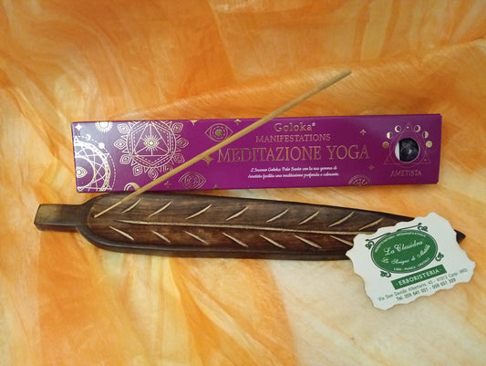 Confezione orizzontale di Incenso Goloka Manifestation Meditazione Yoga con Ametista burattata, davanti a un portaincenso artigianale a forma di foglia con stick, biglietto da visita dell’Erboristeria La Clessidra Carpi e sfondo con telo sfumato in toni aranciati orientali.