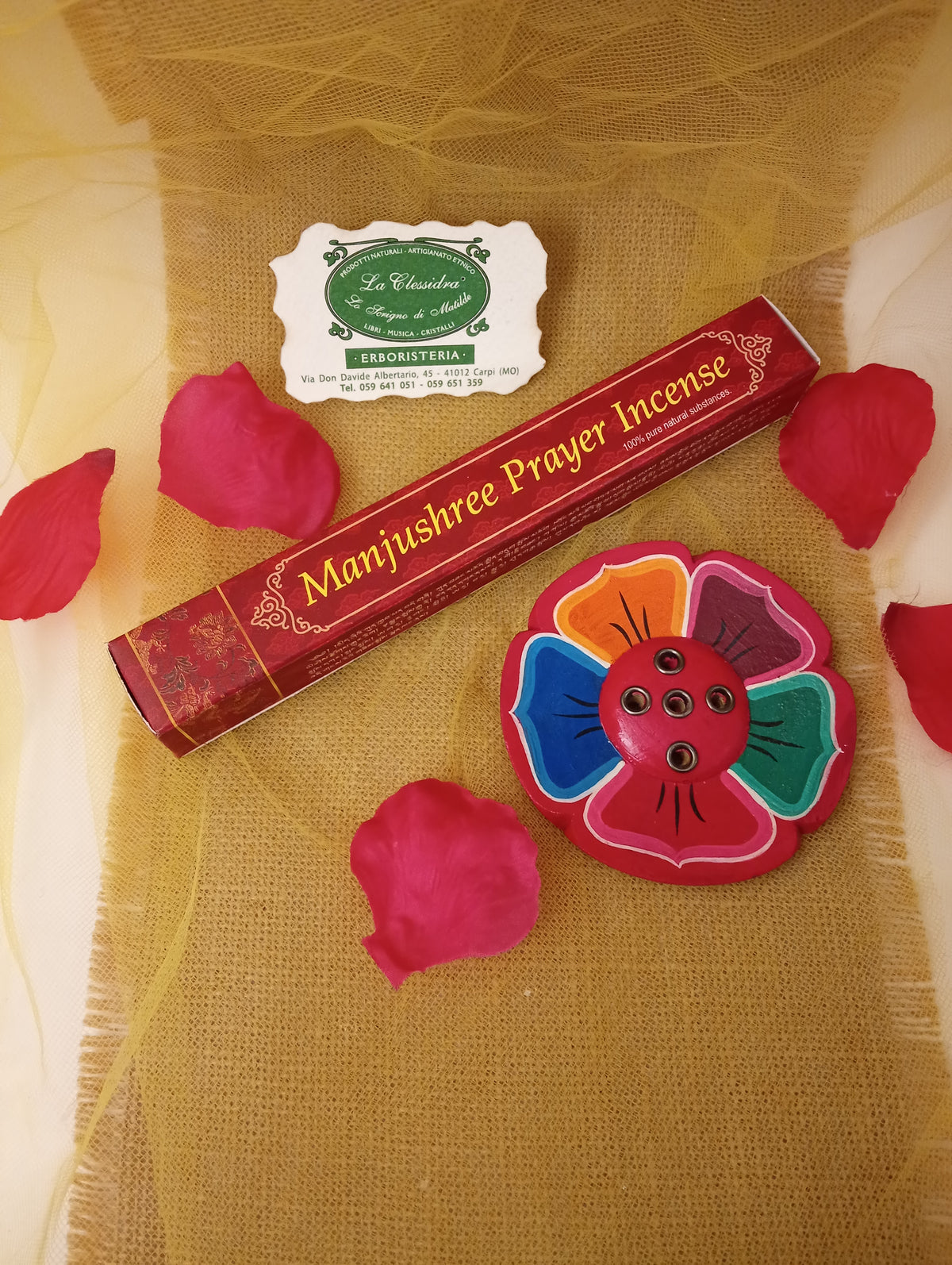 Confezione di incenso tibetano Manjushree Prayer Himalayan Arts con portaincenso a fiore colorato, petali di rosa e biglietto di Erboristeria La Clessidra Carpi su tessuto dorato