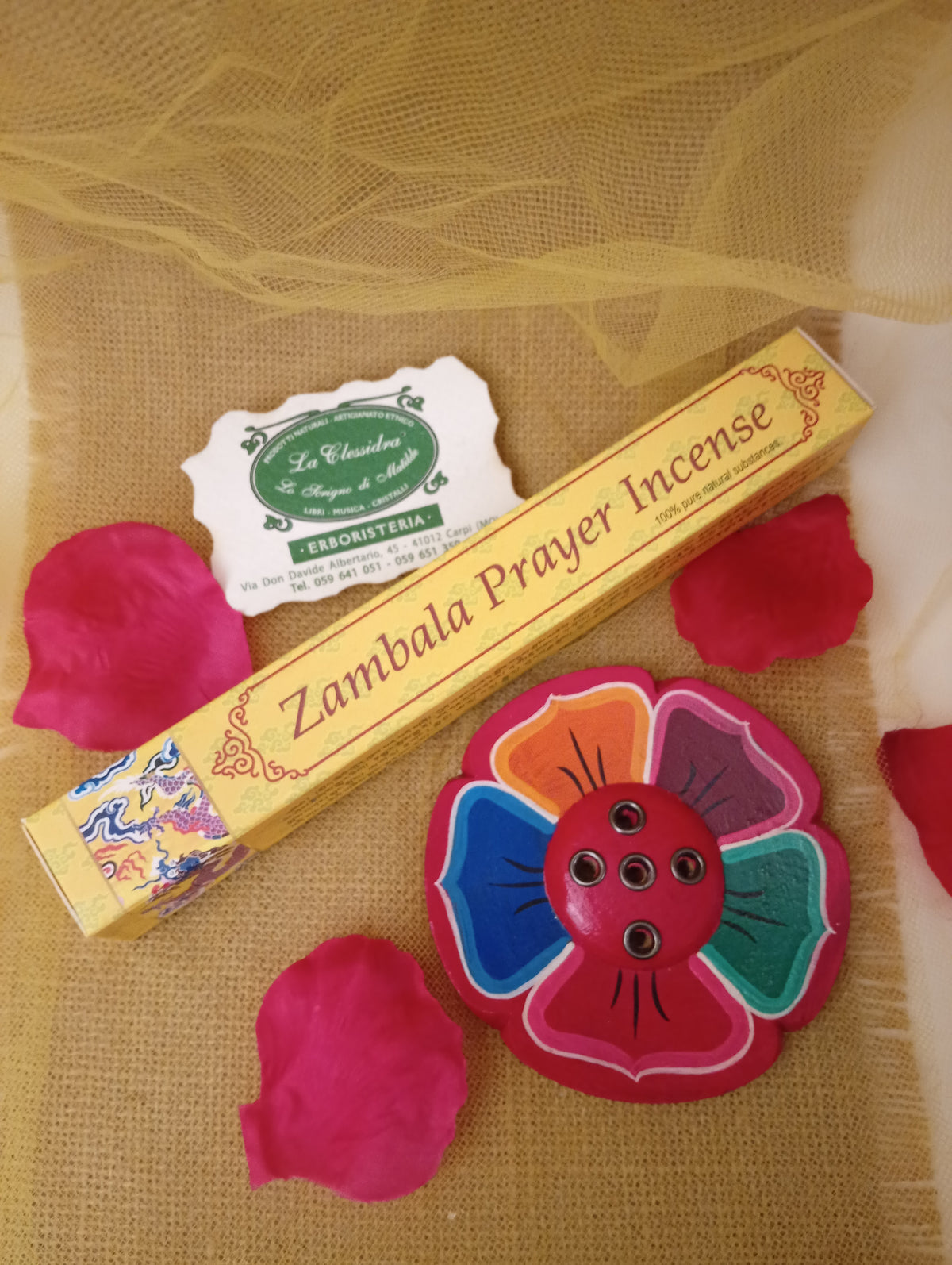 Confezione di incenso tibetano Zambala Prayer Himalayan Arts con portaincenso a fiore colorato, petali di rosa e biglietto di Erboristeria La Clessidra Carpi su tessuto dorato