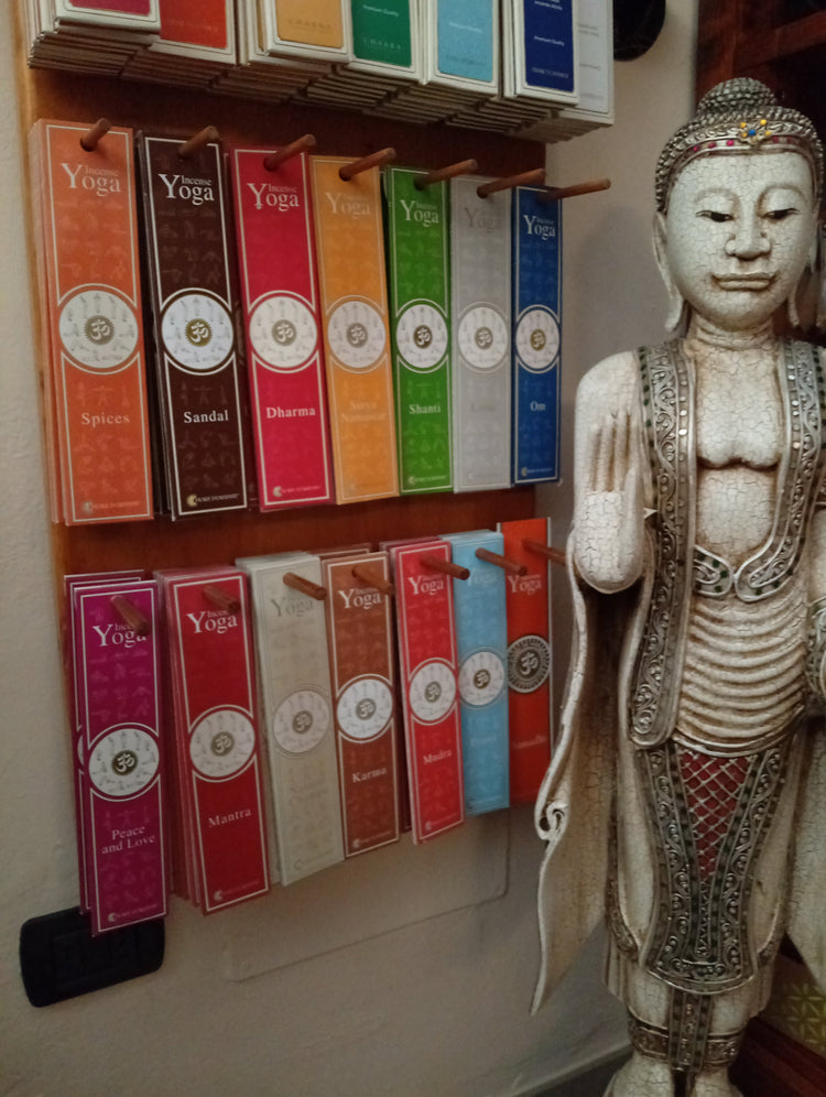 Collezione Incensi Fiore d'Oriente Linea Yoga ed Energie esposta a parete nell'erboristeria La Clessidra di Carpi, con statua di Buddha
