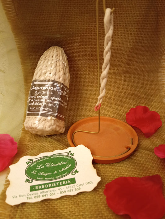 Incenso a corda nepalese Agarwood, con confezione marrone e treccia sospesa sopra un piattino in terracotta all’Erboristeria La Clessidra Carpi