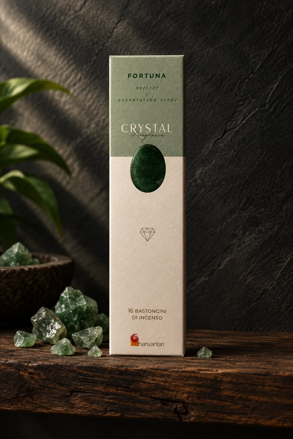 Astuccio rettangolare verticale di Incenso Crystal Fragrance Fortuna Dhanvantari su mensola di legno scuro davanti a una parete di ardesia con frammenti grezzi di avventurina verde, da Erboristeria La Clessidra Carpi