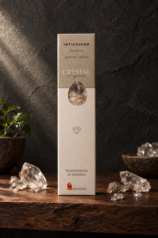 Astuccio rettangolare verticale di Incenso Crystal Fragrance Intuizione Dhanvantari su mensola di legno scuro davanti a una parete di ardesia con frammenti grezzi di cristallo di quarzo ialino, da Erboristeria La Clessidra Carpi
