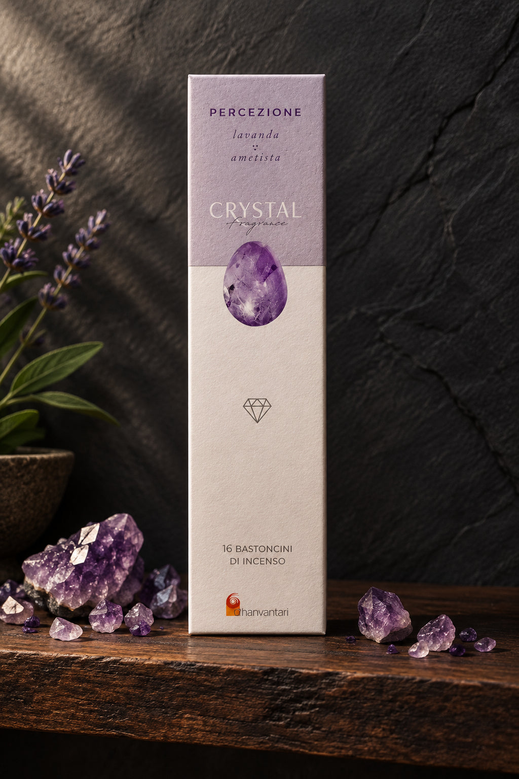 Astuccio rettangolare verticale di Incenso Crystal Fragrance Percezione Dhanvantari su mensola di legno scuro davanti a una parete di ardesia con frammenti grezzi di cristallo di ametista viola, da Erboristeria La Clessidra Carpi