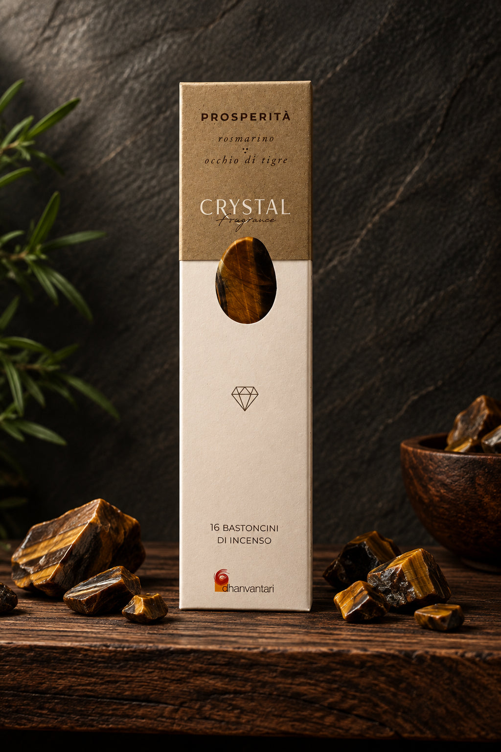 Astuccio rettangolare verticale di Incenso Crystal Fragrance Prosperità Dhanvantari su mensola di legno scuro davanti a una parete di ardesia con frammenti grezzi di pietra occhio di tigre, da Erboristeria La Clessidra Carpi.