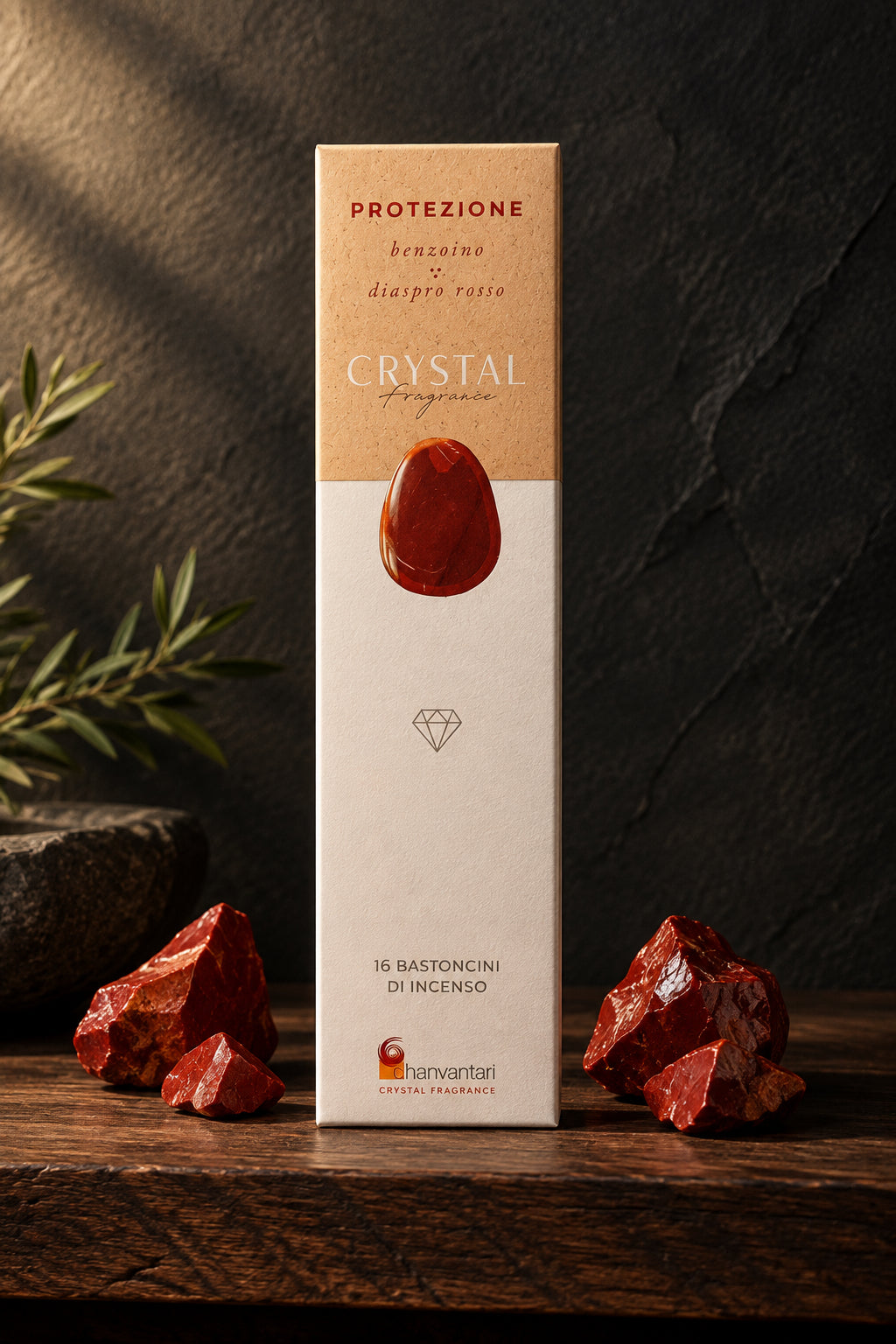 Astuccio rettangolare verticale di Incenso Crystal Fragrance Protezione Dhanvantari su mensola di legno scuro davanti a una parete di ardesia con frammenti grezzi di pietra diaspro rosso, da Erboristeria La Clessidra Carpi.