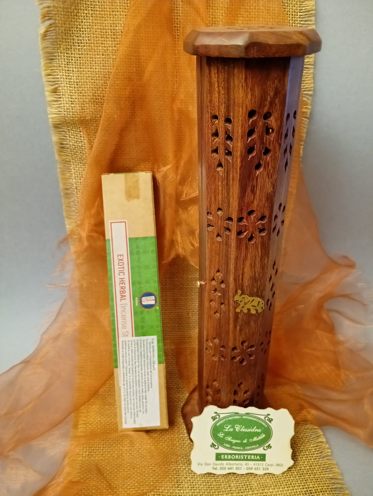 Incenso Shrinivas Exotic Herbal accanto a un portaincenso in legno traforato nel negozio La Clessidra a Carpi.