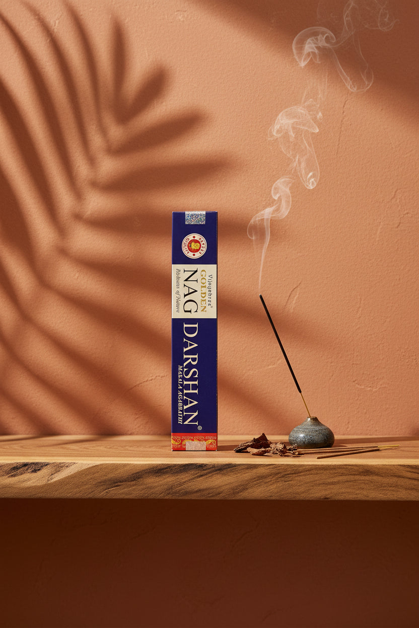Astuccio di Incenso Golden Nag Darshan Vijayshree su mensola di legno grezzo davanti a parete terracotta con ombre di foglie di palma, portaincenso artigianale con stick e scaglie di corteccia, da Erboristeria La Clessidra Carpi
