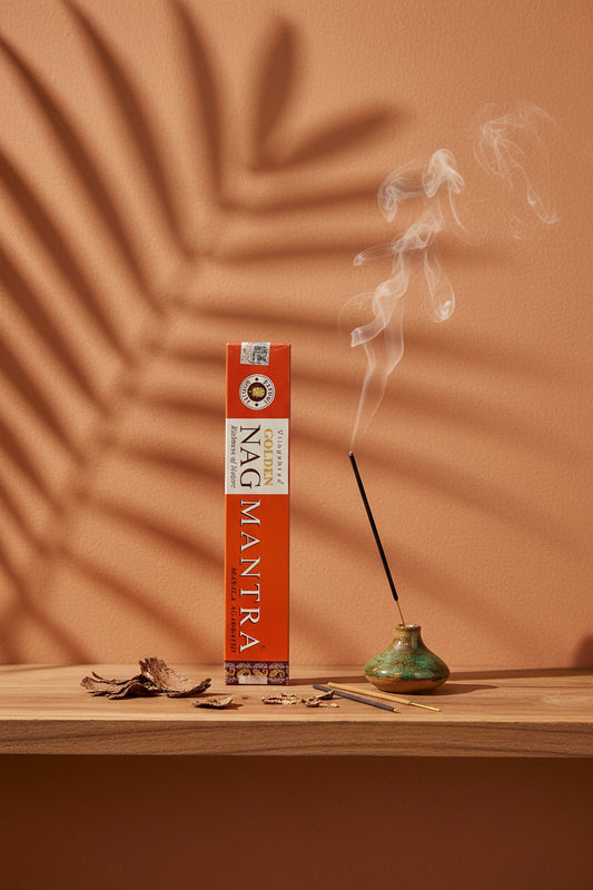 Astuccio di Incenso Golden Nag Mantra Vijayshree su mensola di legno grezzo davanti a parete terracotta con ombre di foglie di palma, portaincenso artigianale con stick e scaglie di corteccia, da Erboristeria La Clessidra Carpi