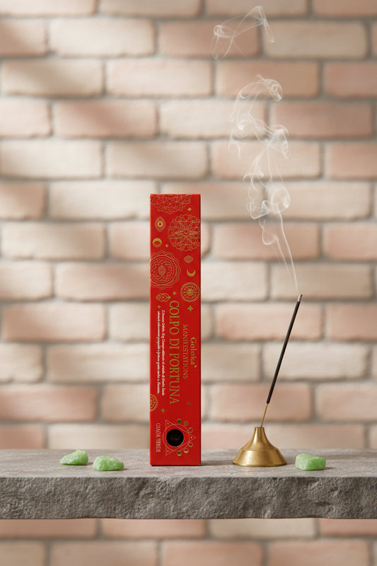 Astuccio Incenso Goloka Manifestation Colpo di Fortuna su mensola di pietra con frammenti di Giada Verde, portaincenso metallico con stick acceso e muro antico, da Erboristeria La Clessidra Carpi.