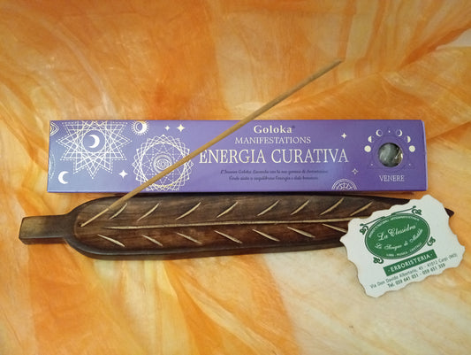 Confezione orizzontale di Incenso Goloka Manifestation Energia Curativa con Avventurina Verde burattata, davanti a un portaincenso artigianale a forma di foglia con stick, biglietto da visita dell’Erboristeria La Clessidra Carpi e sfondo con telo sfumato in toni aranciati orientali.