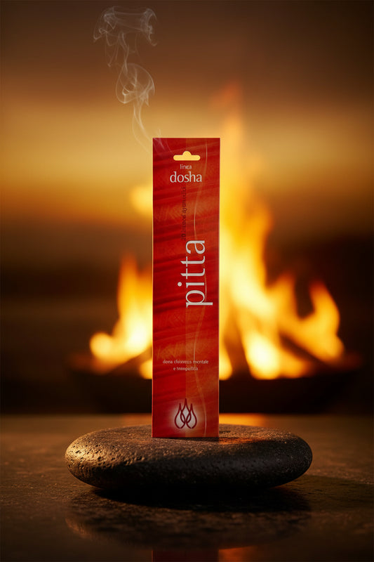 Astuccio incenso ayurvedico Linea Dosha Pitta Dhanvantari esposto su pietra lavica scura tra riflessi dorati e bagliori caldi di Erboristeria La Clessidra Carpi