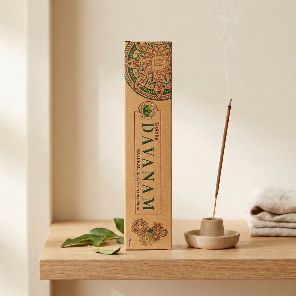 Incenso Goloka Natural Davanam su legno chiaro, accanto a un bastoncino acceso e foglie verdi.
