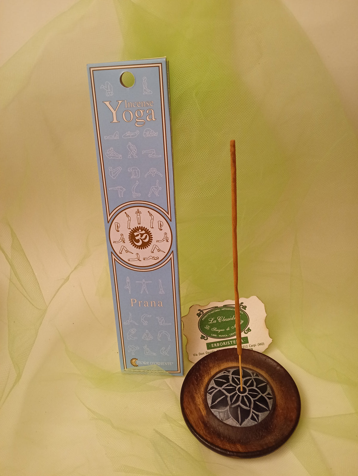 Dettaglio astuccio incenso Prana Fiore d'Oriente in un bruciatore artigianale con velo color verde e biglietto da visita Erboristeria La Clessidra Carpi