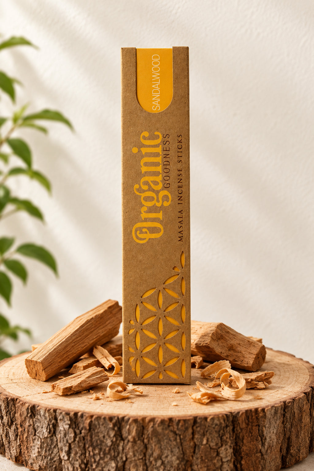 Confezione in cartone kraft di Incenso Organic Goodness Sandalwood Song of India in verticale su sezione di tronco di legno con piccoli pezzi di legno di sandalo, da Erboristeria La Clessidra Carpi