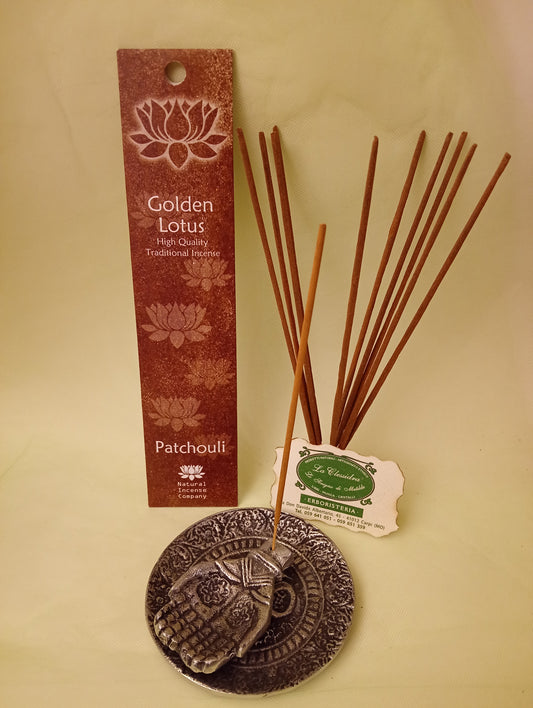 Incenso Patchouli Fiore d'Oriente Linea Golden Lotus, astuccio con mazzetto di bastoncini aperti in piedi, portaincenso in metallo con mano e biglietto da visita esposti da Erboristeria La Clessidra Carpi.