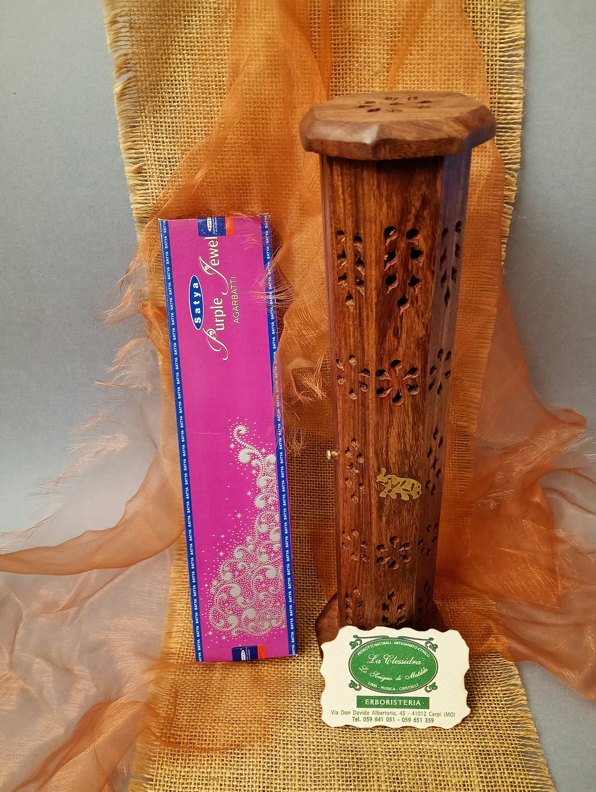 Incenso Satya Purple Jewel accanto a un portaincenso in legno traforato nel negozio La Clessidra a Carpi.
