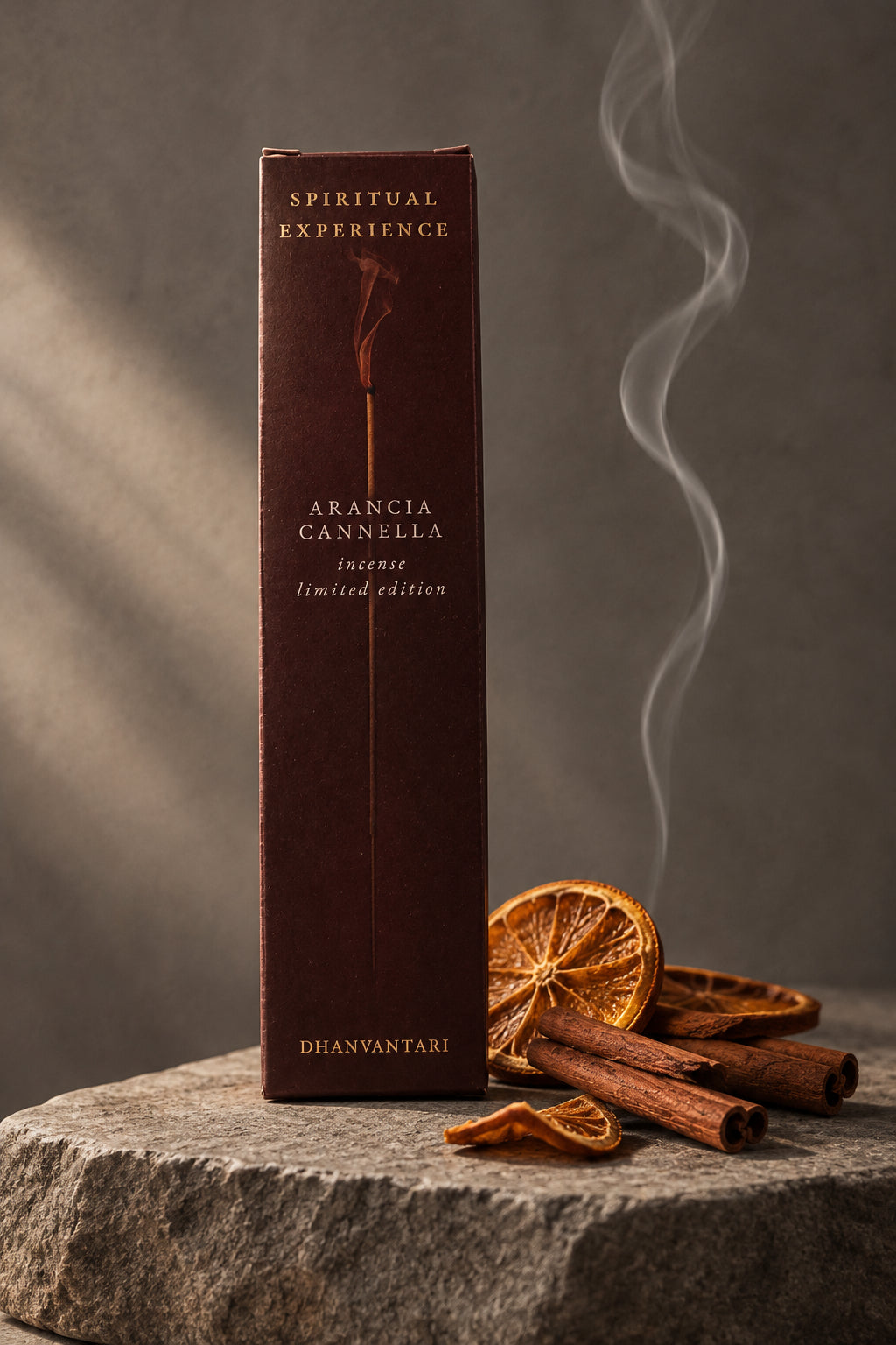 Astuccio rettangolare di Incenso Spiritual Experience Arancia Cannella Dhanvantari in verticale su lastra di pietra grigia davanti a parete scura con fette d'arancia e cannella, da Erboristeria La Clessidra Carpi