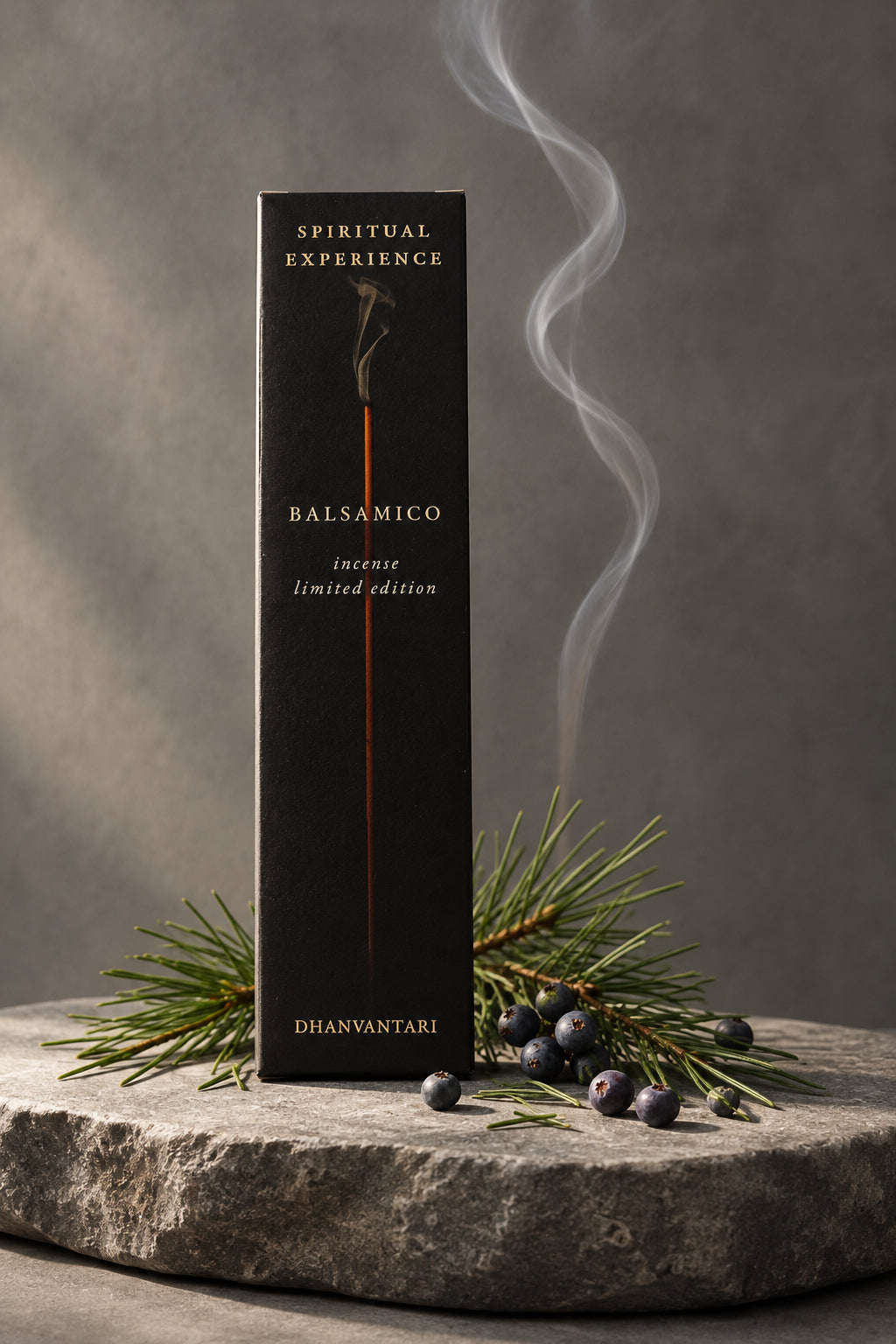 Astuccio rettangolare di Incenso Spiritual Experience Balsamico Dhanvantari in verticale su lastra di pietra grigia davanti a parete scura con aghi di pino, da Erboristeria La Clessidra Carpi.