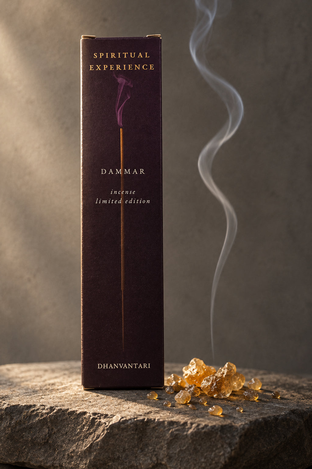 Astuccio rettangolare di Incenso Spiritual Experience Dammar Dhanvantari in verticale su lastra di pietra grigia davanti a parete scura con grani di resina dorata, da Erboristeria La Clessidra Carpi