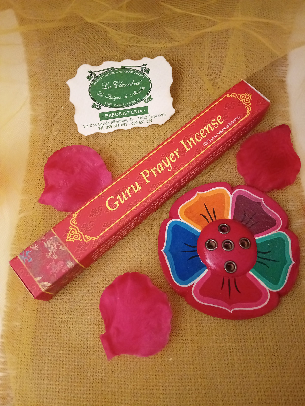 Confezione di incenso tibetano Guru Prayer Himalayan Arts con portaincenso a fiore colorato, petali di rosa e biglietto di Erboristeria La Clessidra Carpi su tessuto dorato
