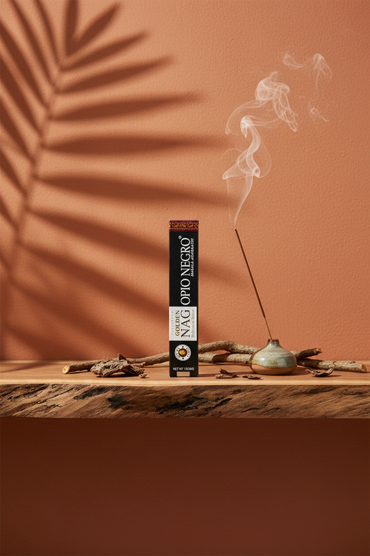 Astuccio di Incenso Golden Nag Opio Negro (Oppio Nero) Vijayshree su mensola di legno grezzo davanti a parete terracotta con ombre di foglie di palma, portaincenso artigianale con stick e scaglie di corteccia, da Erboristeria La Clessidra Carpi.